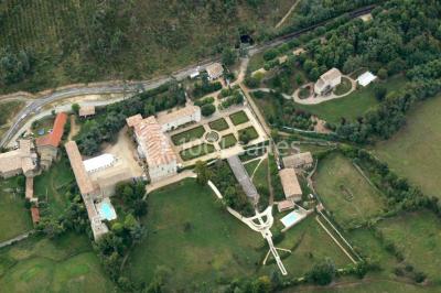 Vue aérienne d'un domaine avec jardins symétriques, bâtiments en pierre, piscine et espaces verts environnants.