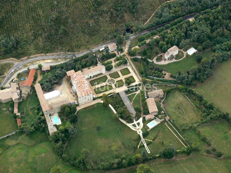 Vue aérienne d'un domaine avec jardins symétriques, bâtiments en pierre, piscine et espaces verts environnants.