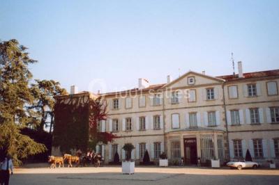 Vue aérienne d'un domaine avec jardins symétriques, bâtiments en pierre, piscine et espaces verts environnants.
