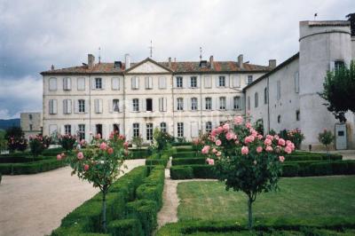 Vue aérienne d'un domaine avec jardins symétriques, bâtiments en pierre, piscine et espaces verts environnants.