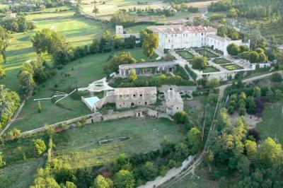 Vue aérienne d'un domaine avec jardins symétriques, bâtiments en pierre, piscine et espaces verts environnants.
