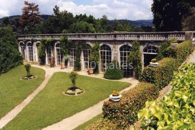 Vue aérienne d'un domaine avec jardins symétriques, bâtiments en pierre, piscine et espaces verts environnants.