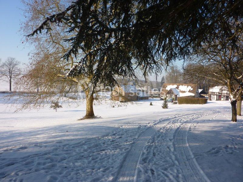 Paysage enneigé avec des maisons rurales, des arbres dénudés et des traces de passage dans la neige.