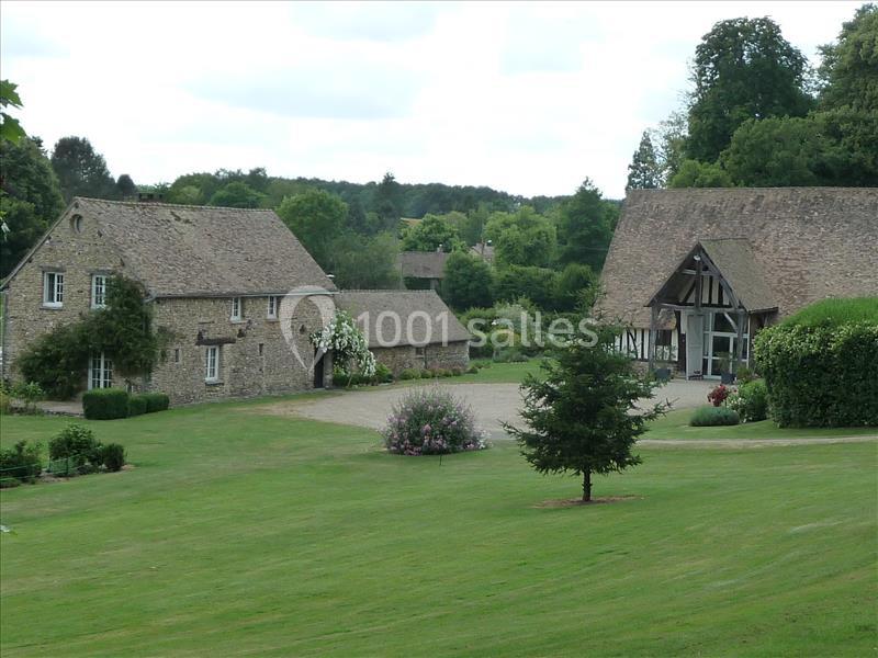 Vue d'un ensemble de bâtiments en pierre avec toits en ardoise, entourés de pelouses et de végétation.
