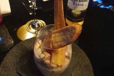 Planche de charcuterie et fromages sur une table en terrasse, avec une bouteille de vin blanc dans un seau à glace.