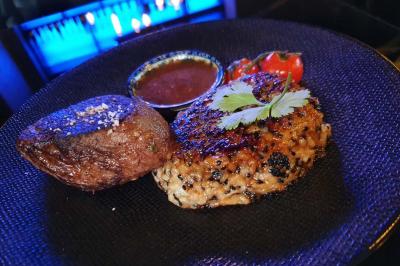 Planche de charcuterie et fromages sur une table en terrasse, avec une bouteille de vin blanc dans un seau à glace.