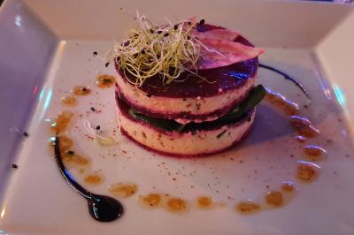 Planche de charcuterie et fromages sur une table en terrasse, avec une bouteille de vin blanc dans un seau à glace.