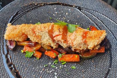 Planche de charcuterie et fromages sur une table en terrasse, avec une bouteille de vin blanc dans un seau à glace.
