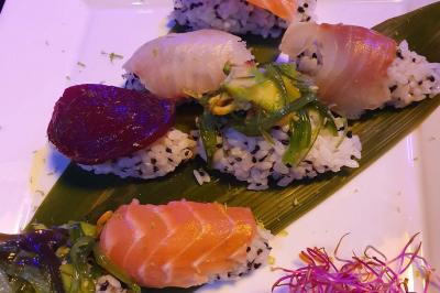 Planche de charcuterie et fromages sur une table en terrasse, avec une bouteille de vin blanc dans un seau à glace.
