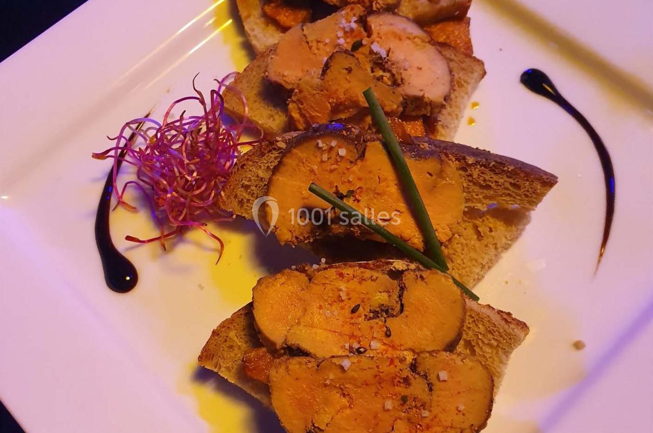 Tranches de foie gras sur pain grillé, décorées de ciboulette, réduction balsamique et pousses colorées.