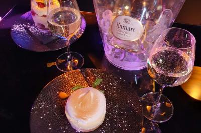 Planche de charcuterie et fromages sur une table en terrasse, avec une bouteille de vin blanc dans un seau à glace.