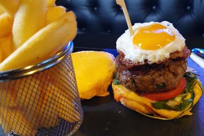 Planche de charcuterie et fromages sur une table en terrasse, avec une bouteille de vin blanc dans un seau à glace.