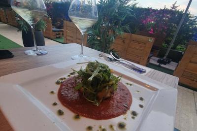 Planche de charcuterie et fromages sur une table en terrasse, avec une bouteille de vin blanc dans un seau à glace.