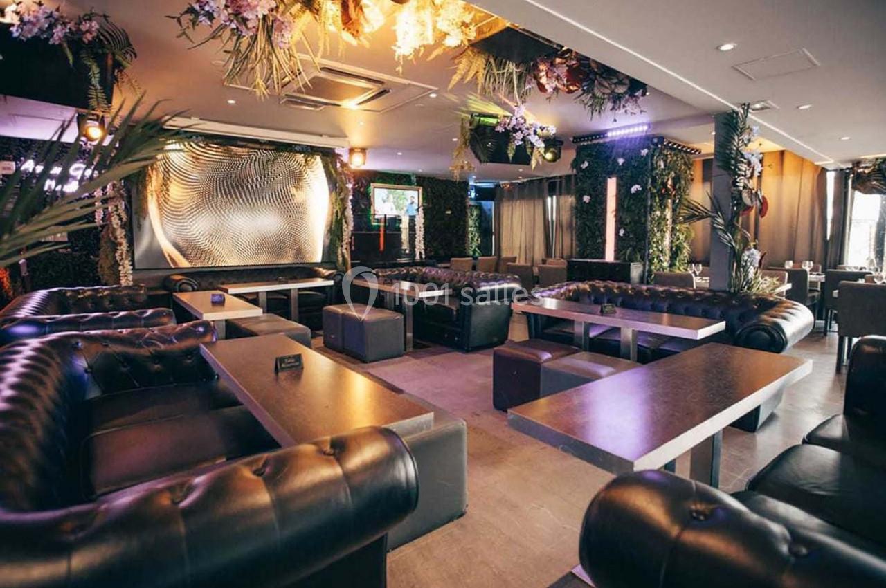 Espace intérieur d'un salon avec canapés en cuir, tables basses et décoration végétale suspendue.