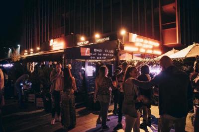 Assiette de viande garnie de roquette et sauce rouge, servie sur une table avec des verres de vin en arrière-plan.