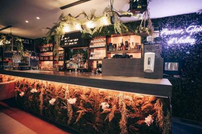 Assiette de viande garnie de roquette et sauce rouge, servie sur une table avec des verres de vin en arrière-plan.