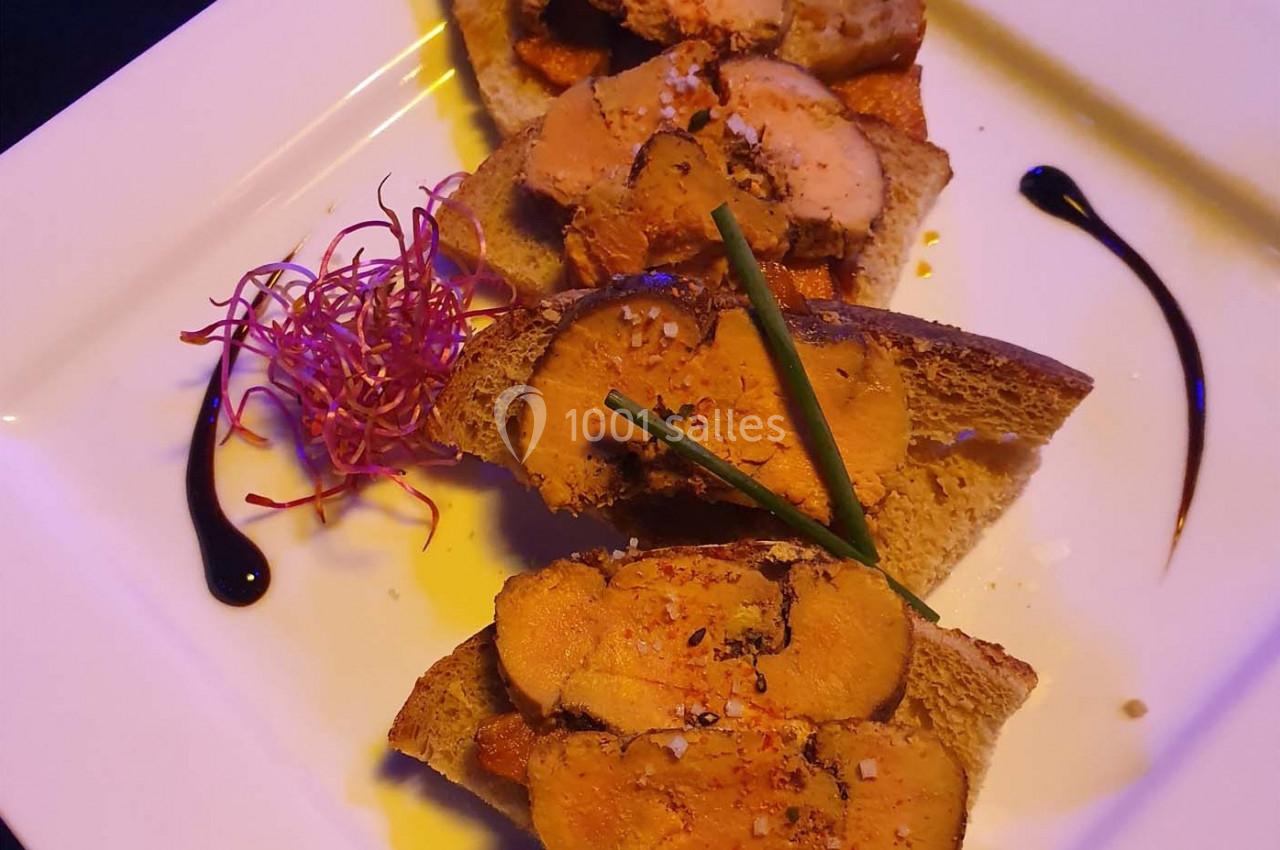 Tranches de foie gras sur pain grillé, décorées de brins de ciboulette, pousses rouges et traits de sauce balsamique.