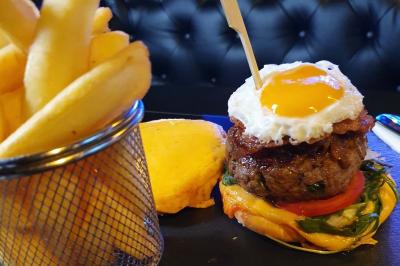 Assiette de viande garnie de roquette et sauce rouge, servie sur une table avec des verres de vin en arrière-plan.