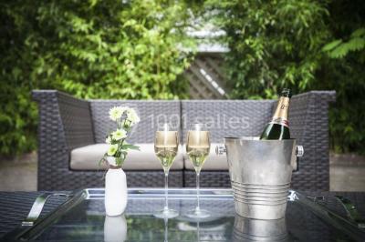 Comptoir de réception en bois avec étagères éclairées contenant des bouteilles et des verres, décoré de plantes séchées.