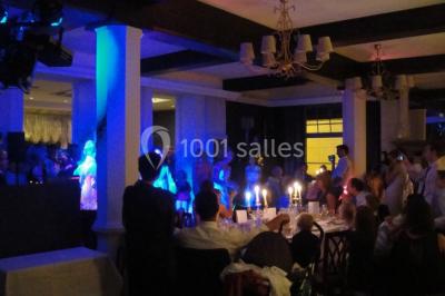 Comptoir de réception en bois avec étagères éclairées contenant des bouteilles et des verres, décoré de plantes séchées.