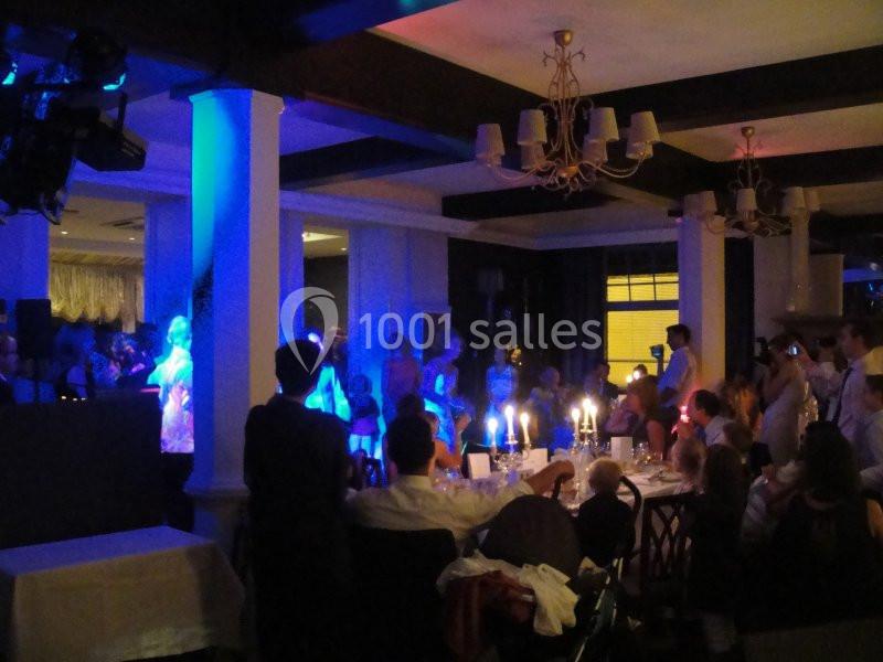 Salle de réception avec des invités assis et debout, éclairée par des bougies et des lumières colorées.