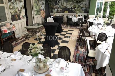 Comptoir de réception en bois avec étagères éclairées contenant des bouteilles et des verres, décoré de plantes séchées.