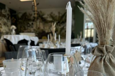 Comptoir de réception en bois avec étagères éclairées contenant des bouteilles et des verres, décoré de plantes séchées.