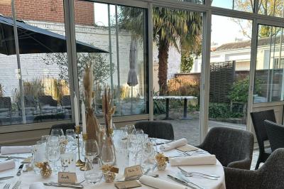 Comptoir de réception en bois avec étagères éclairées contenant des bouteilles et des verres, décoré de plantes séchées.