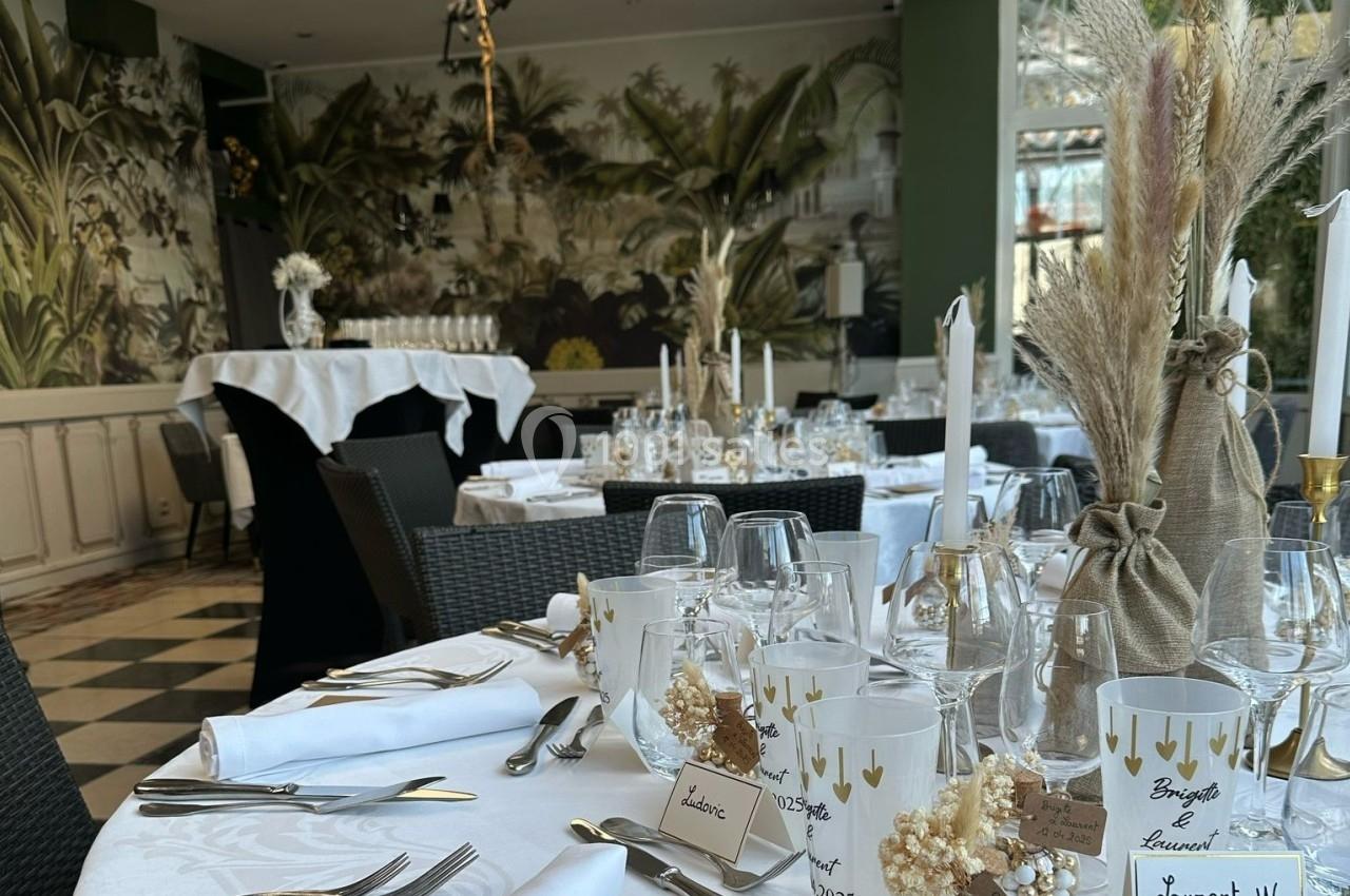 Salle de réception élégamment décorée avec des tables dressées, bougies, fleurs séchées et vaisselle raffinée.