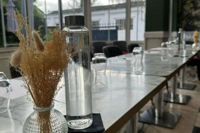 Comptoir de réception en bois avec étagères éclairées contenant des bouteilles et des verres, décoré de plantes séchées.