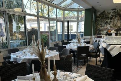 Comptoir de réception en bois avec étagères éclairées contenant des bouteilles et des verres, décoré de plantes séchées.