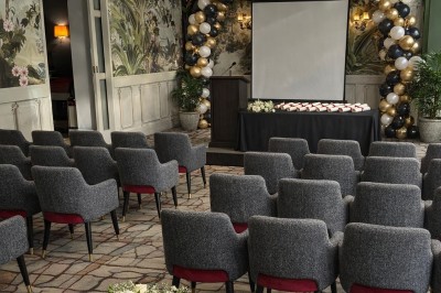 Comptoir de réception en bois avec étagères éclairées contenant des bouteilles et des verres, décoré de plantes séchées.