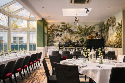 Comptoir de réception en bois avec étagères éclairées contenant des bouteilles et des verres, décoré de plantes séchées.