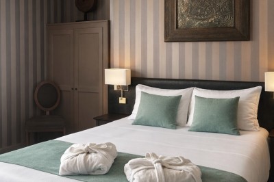 Comptoir de réception en bois avec étagères éclairées contenant des bouteilles et des verres, décoré de plantes séchées.