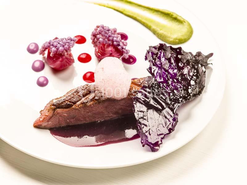 Assiette gastronomique avec viande, purées colorées, mousse légère et décoration de chou violet.
