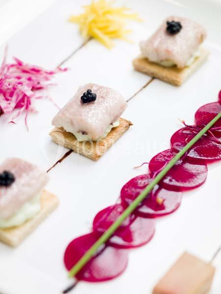 Assiette gastronomique avec toasts garnis de poisson, crème et caviar, accompagnés de betteraves et décorations colorées.