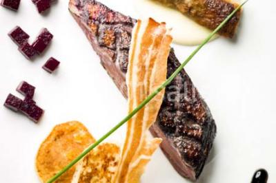 Comptoir de réception en bois avec étagères éclairées contenant des bouteilles et des verres, décoré de plantes séchées.