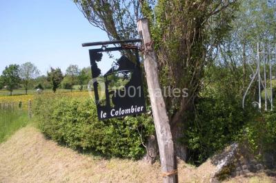 Chambre simple avec un lit double, deux lampes de chevet, des tableaux au mur et une grande fenêtre avec rideaux.