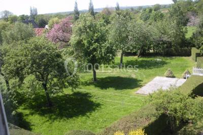 Chambre simple avec un lit double, deux lampes de chevet, des tableaux au mur et une grande fenêtre avec rideaux.