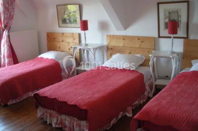 Chambre simple avec un lit double, deux lampes de chevet, des tableaux au mur et une grande fenêtre avec rideaux.