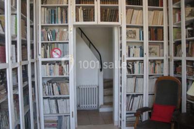 Chambre simple avec un lit double, deux lampes de chevet, des tableaux au mur et une grande fenêtre avec rideaux.