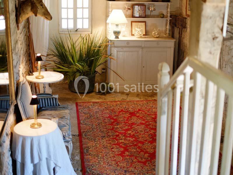 Intérieur chaleureux avec tapis rouge, meubles en bois clair, plantes vertes et lumière naturelle entrant par une fenêtre.