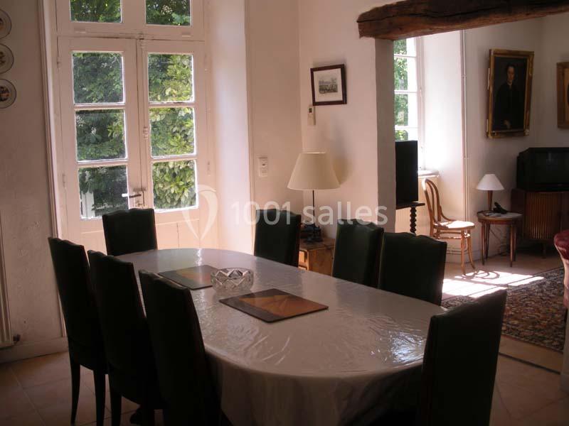 Salle à manger lumineuse avec une grande table recouverte d'une nappe blanche, entourée de chaises noires.