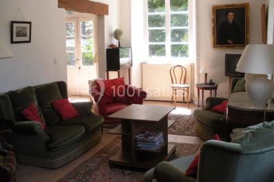 Chambre simple avec un lit double, deux lampes de chevet, des tableaux au mur et une grande fenêtre avec rideaux.