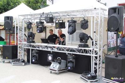 Installation de matériel de sonorisation et d'éclairage avec deux techniciens en train de régler les équipements.