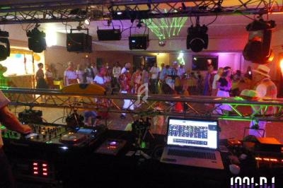 Vue depuis la cabine d'un DJ lors d'une soirée dansante, avec des lumières colorées et une piste animée.