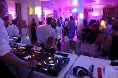 Soirée dansante avec un DJ mixant sur des platines, éclairage coloré et invités sur la piste de danse.
