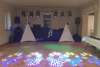 Salle de réception avec éclairage de scène coloré, projecteurs au plafond et espace de danse dégagé.