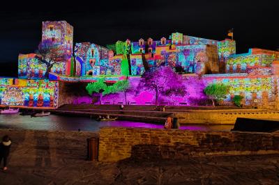 Façade illuminée d'une église avec des projections colorées et des informations sur un événement musical à Collioure.