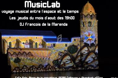 Projection lumineuse colorée sur un bâtiment historique de nuit, annonçant un événement musical à Collioure.